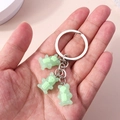 Detail of three light green translucent bear charms with skull patterns on a silver keychain - Light Green