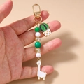 Gros plan d'un porte-clés perlé avec breloques alpaga et cactus tenu à la main - Cactus en Pot Lama