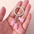 Detail of hand holding a silver keyring with three pink skeleton bear charms - Light Pink