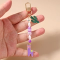 Porte-clés en perles avec breloques alpaga violet et cactus vert tenu dans la main - Cactus Lama Violet