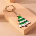 Detailaufnahme eines grünen Weihnachtsbaum-Schlüsselanhängers mit silbernem Ring auf Podest - Schneeflocke Weihnachtsbaum