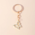 Porte-clés papillon ajouré en or rose avec strass brillants sur fond rose élégant - Doré