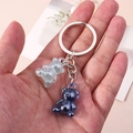 Handheld view of cartoon bear keychains in translucent green and glossy blue finishes - Teal
