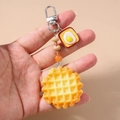 Dettaglio di un portachiavi di perline con ciondoli a forma di waffle e toast all'uovo - Pane Biscotto Waffle