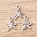 Detailed macro view of three silver alloy starfish pendants on light wood background - 30Pcs Pack / Large Starfish