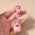 Detail of pink woven basket charm with matching plastic chain and metal bell accessory - Pink