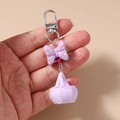 Detalle de llavero con lazo de resina púrpura y dije de cesta tejida en primer plano - Morado
