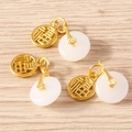 Dettaglio di tre ciondoli in giada bianca con charms dorati Fu su sfondo di legno - Confezione da 10 / Finta Giada Bianca