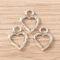 Drei Vintage-Silber-Herzanhänger mit Ösen auf hellem Holzgrund für DIY-Schmuck - Großes Hohles Herz