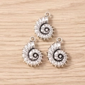 Drie antieke zilveren nautilus-bedeltjes voor DIY-sieraden op een houten ondergrond - Schelp
