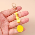 Close-up of yellow beaded smiley face keychain with golden lobster clasp for bags - Yellow