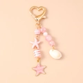 Dettaglio di ciondoli con conchiglie rosa e stelle marine su chiusura a cuore dorato - Shell Starfish