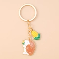 Detailansicht eines goldenen Schlüsselanhängers mit Emaille-Igel und kleinem Maiskolben-Anhänger - Mais-Igel