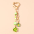 Detail eines goldenen Herzverschlusses mit grünen Perlen und Gänseblümchen-Anhängern - Grüne Blume