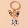 Detailed close-up of Halloween keychain featuring gold spider and cobweb charms on pink base - Spider Web