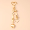 Dettaglio del portachiavi a cuore dorato con simbolo infinito, perle e strass brillanti - Cuore