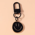 Detail des kreativen Metall-Smiley-Schlüsselanhängers mit schwarzem Lack und Goldfinish - Schwarz