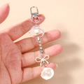 Detail of keychain with rhinestone chain, white resin bow and pearl shell pendant - White Flower Shell