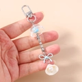 Detail of seashell charm with pearl, rhinestone chain, and light blue bow on keychain - Blue Flower Shell