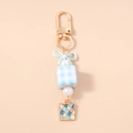 Détail de nœud bleu, perles et cube à carreaux sur un porte-clés en émail tendance - Bleu