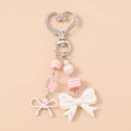 Detail of pink and pearl white beaded bag charm with heart hook and ribbon bows - Pink