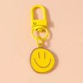 Detailansicht eines gelben Smiley-Schlüsselanhängers mit Karabiner auf weichem Hintergrund - Gelb