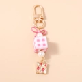 Détail d'un porte-clés ruban rose avec cube à carreaux et perles pour sac à main - Rose