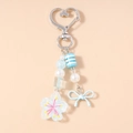 Close-up of sky blue beaded bag charm with bow, cherry blossom pendant and heart clasp - Blue