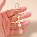 Detalle de llavero dorado con perlas, cadenas de diamantes y un colgante de concha - Estilo de Perla Cadena Strass y Concha