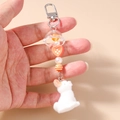 Dettaglio di un coniglio bianco floccato con perla a cuore arancione e nappine chic - Stile Cuore Bottone