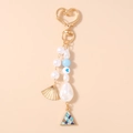 Detalle de llavero de cuentas con mosquetón de corazón dorado y colgante de concha - Concha Azul
