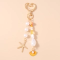Detalle de llavero náutico con cierre de corazón, perlas, estrella de mar y dije de concha - Estrella de Mar Naranja