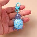 Llavero de tortuga de resina púrpura con patrón geométrico azul sostenido en la mano - Azul claro