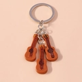 Llavero de guitarra con tres colgantes de resina marrón y un aro de acero inoxidable - Guitarra