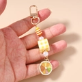 Détail de porte-clés perlé avec un charm en tranche de citron et motifs à carreaux - Porte-clés Cube Citron Jaune
