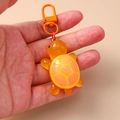Detalle de un llavero de tortuga naranja hecho de resina con textura y cierre de metal - Naranja
