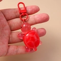 Detalle de llavero de tortuga en resina roja con textura de caparazón y cierre de mosquetón - Rojo