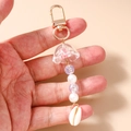 Detalle de llavero de perlas oceánico con dije de medusa y colgante de concha blanca - Rosa