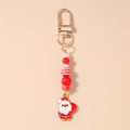 Detalle de colgante de Papá Noel esmaltado con cuentas a rayas en llavero dorado - Santa Claus