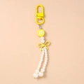 Detalle de llavero amarillo con lazo y borla de perlas blancas de imitación - Amarillo
