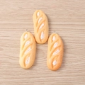 Detail view of miniature resin baguette charms with silver metal rings on a wood surface - Baguette Bread / Set of 4
