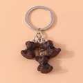 Dettaglio di tre orsetti in resina marrone con fiocchi neri su un anello portachiavi argento - Orso bruno