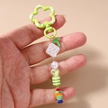 Detail view of goldfish keychain with striped beads and a green letter T charm - Multicolor Pearl Beaded Goldfish