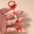 Detail van rode zeester sleutelhanger met witte stippen en een bloemvormige sluiting - Rood