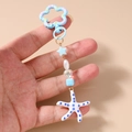 Detailopname van de oceaan-sleutelhanger met blauwe zeester en kralen in de hand - Blauw