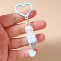 Détail d'un porte-clés perlé bleu clair avec mousqueton coeur et perle cube à carreaux - Bleu
