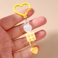 Détail du porte-clés à perles de cœur jaunes avec charms transparents et cube à carreaux - Jaune
