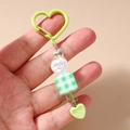Détail d'un porte-clés coeur vert avec perles et pendentif cube à motif damier - Vert