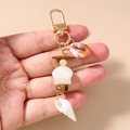 Detail of beaded starfish keychain with natural shells and tiger eye stones held in hand - Conch Gravel Shell Style