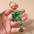 Detail van een kerstboom sleutelhanger met groene kralen en gouden hartvormige sluiting - Kerstboom Kralen Bel Stijl